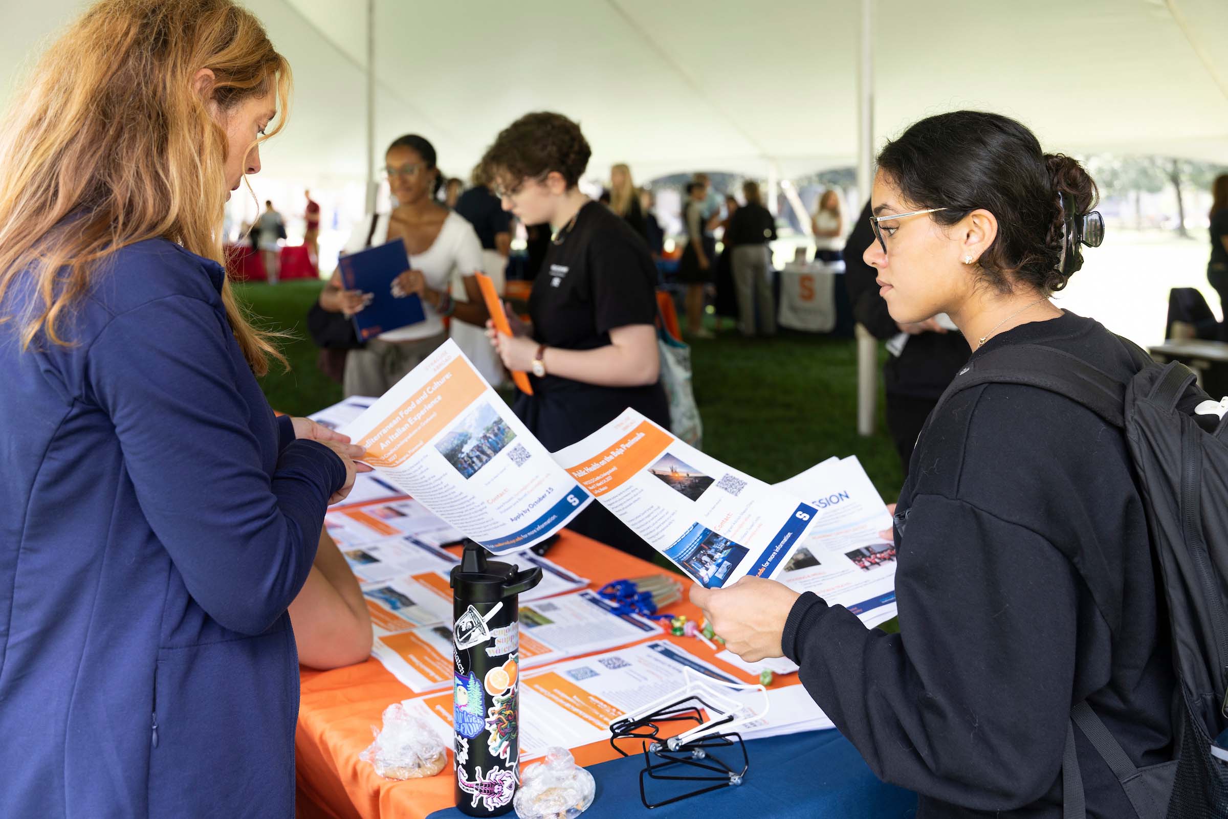 Two people look over flyers for study abroad opportunities.