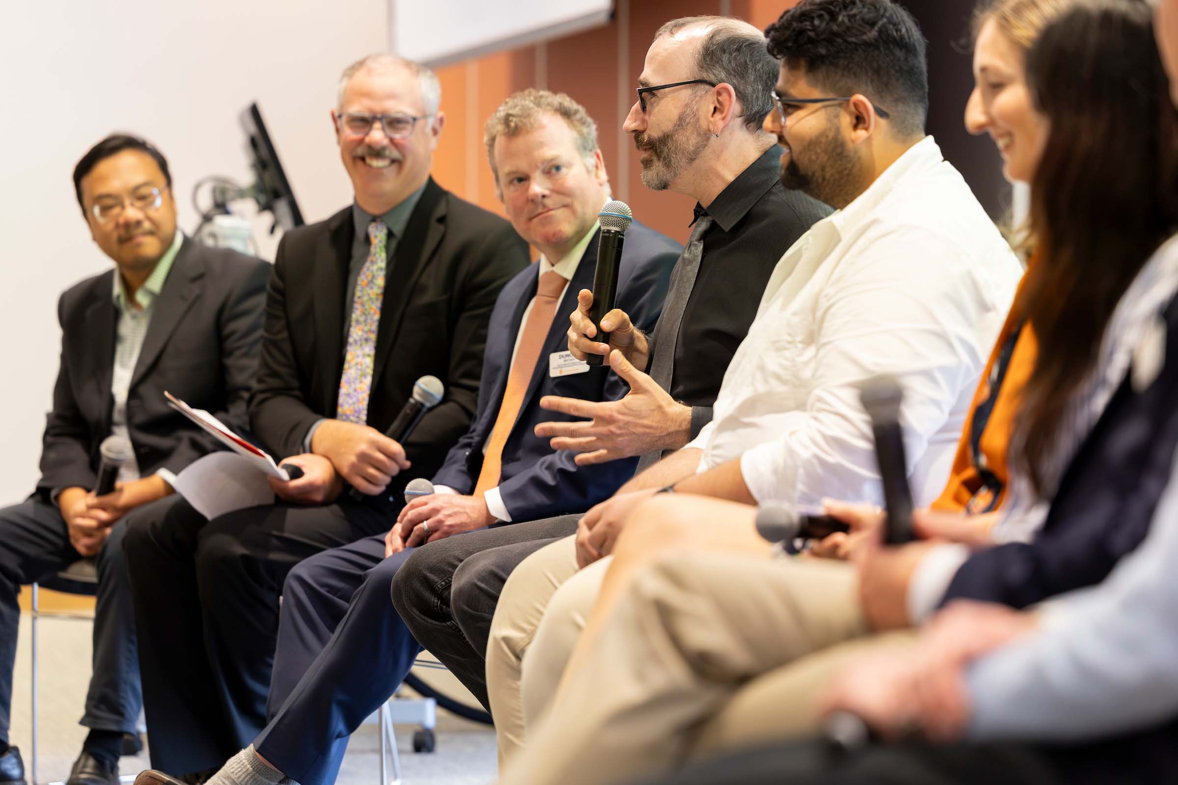 Six people seated and intently listening to a panelist as part of a presentation.
