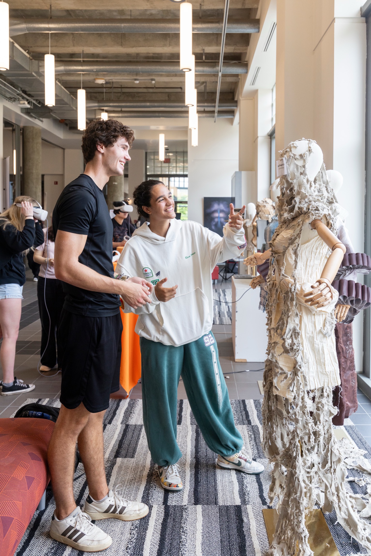 Two students look at an artwork draped over a mannequin