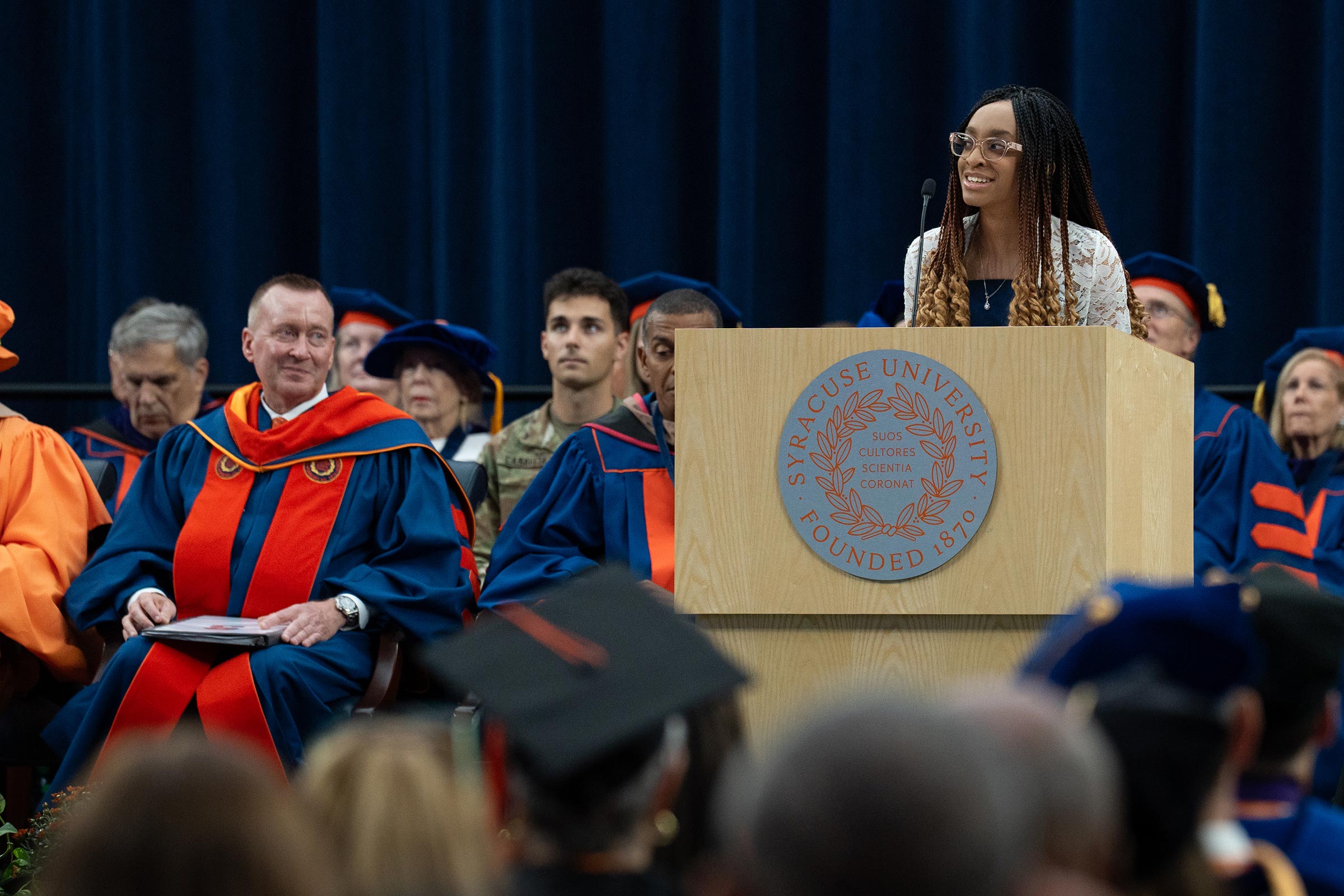 The youth poet laureate shares a poem she wrote for the inauguration, standing at the podium, with the Chancellor looking on.