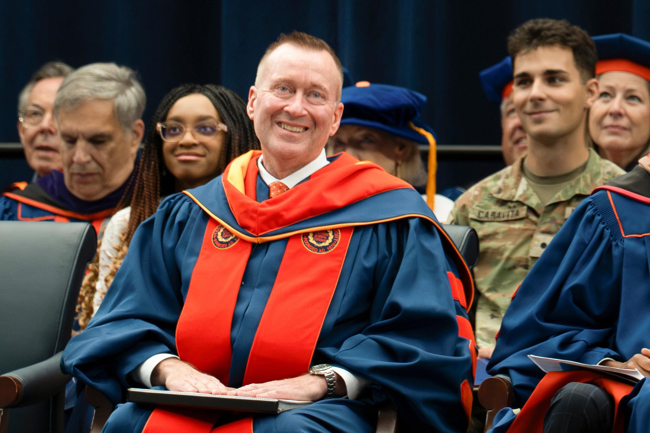 Chancellor Mike Haynie smiles as he listens to a speaker during the ceremony. Seated behind him are guests and other speakers.