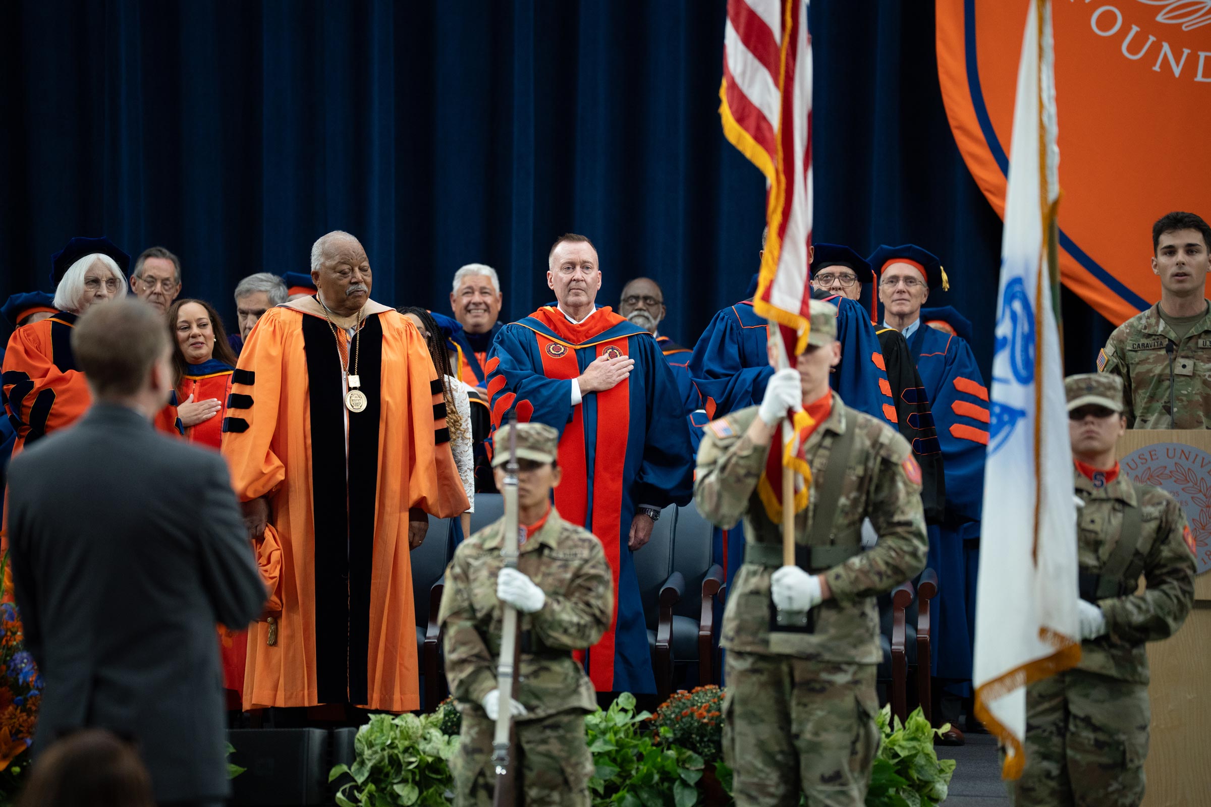 Chancellor Haynie salutes the flag with other leaders on stage at the start of the inauguration ceremony.