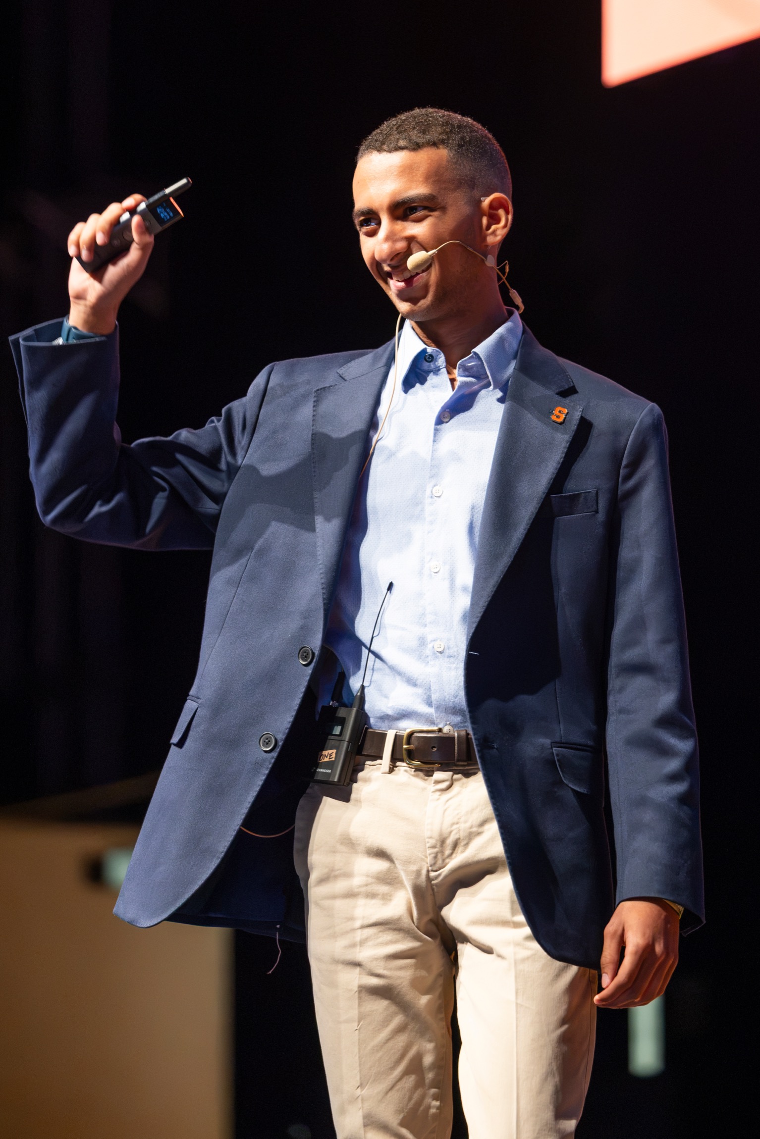 A man presents on stage and holds a microphone in his hands