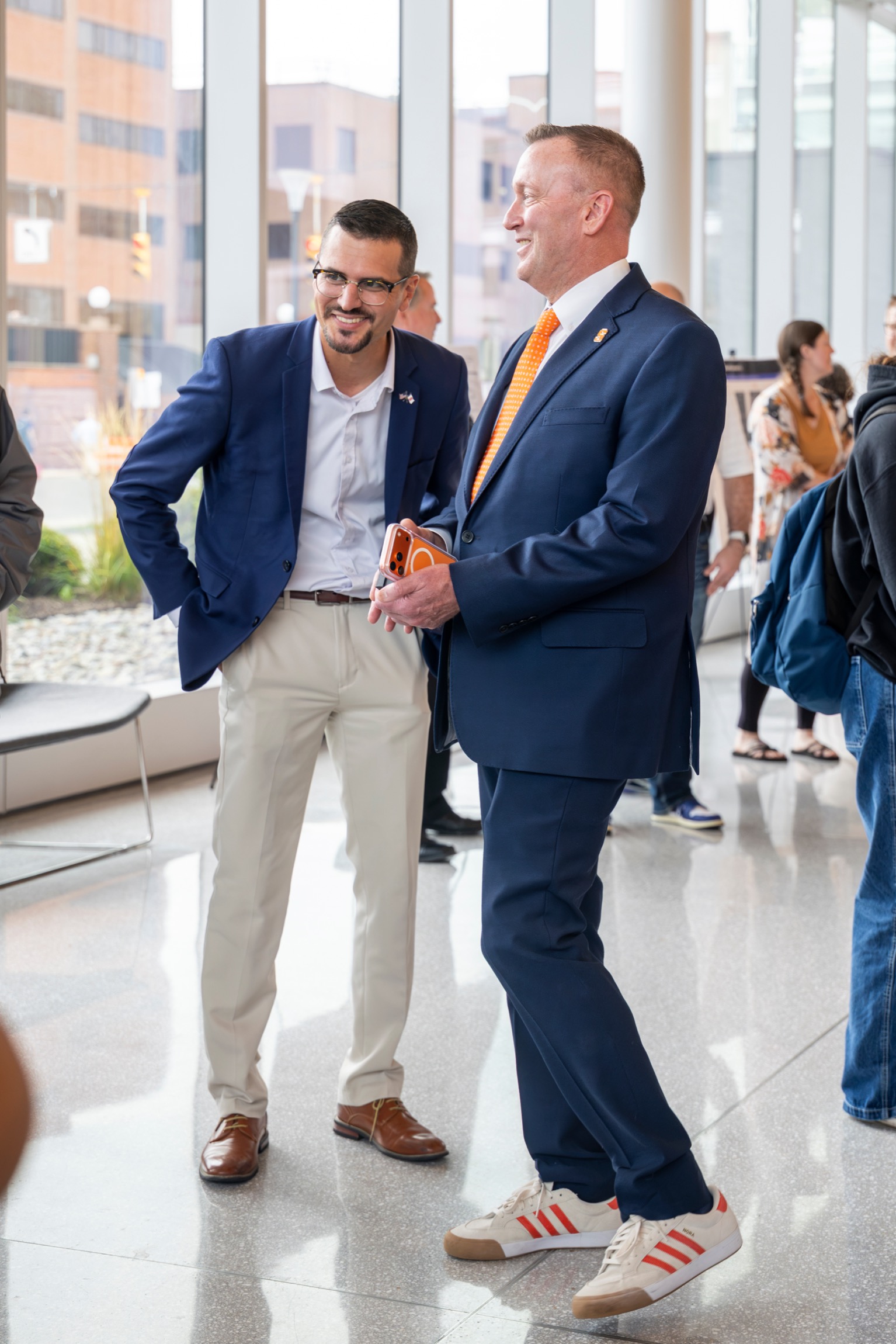 Two men laugh with each other in between presentations. 
