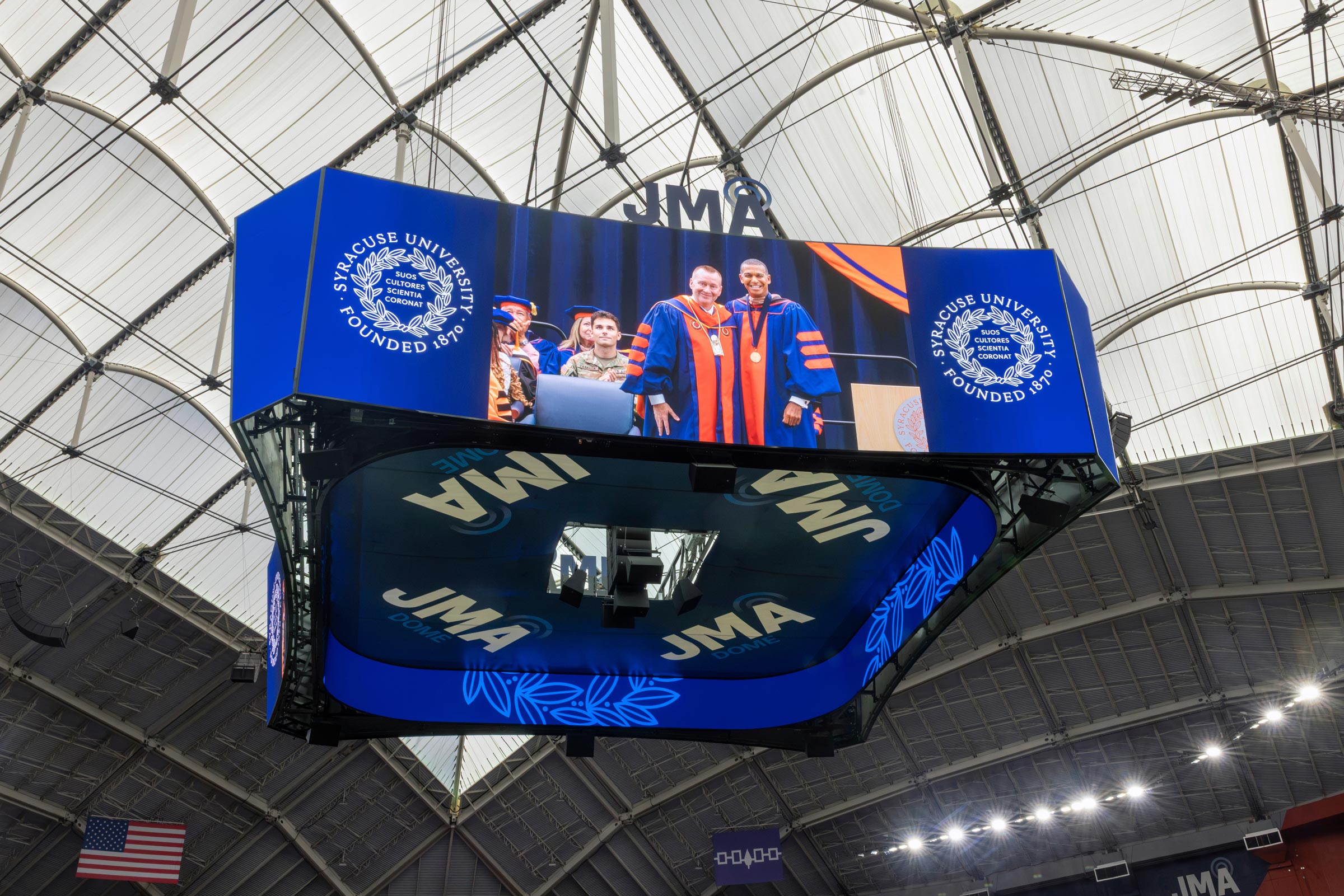 The chancellor and Board Chair, Jeff Scruggs, stand side by side in a video shown on the jumbotron that hangs from the ceiling of the JMA Wireless Dome 