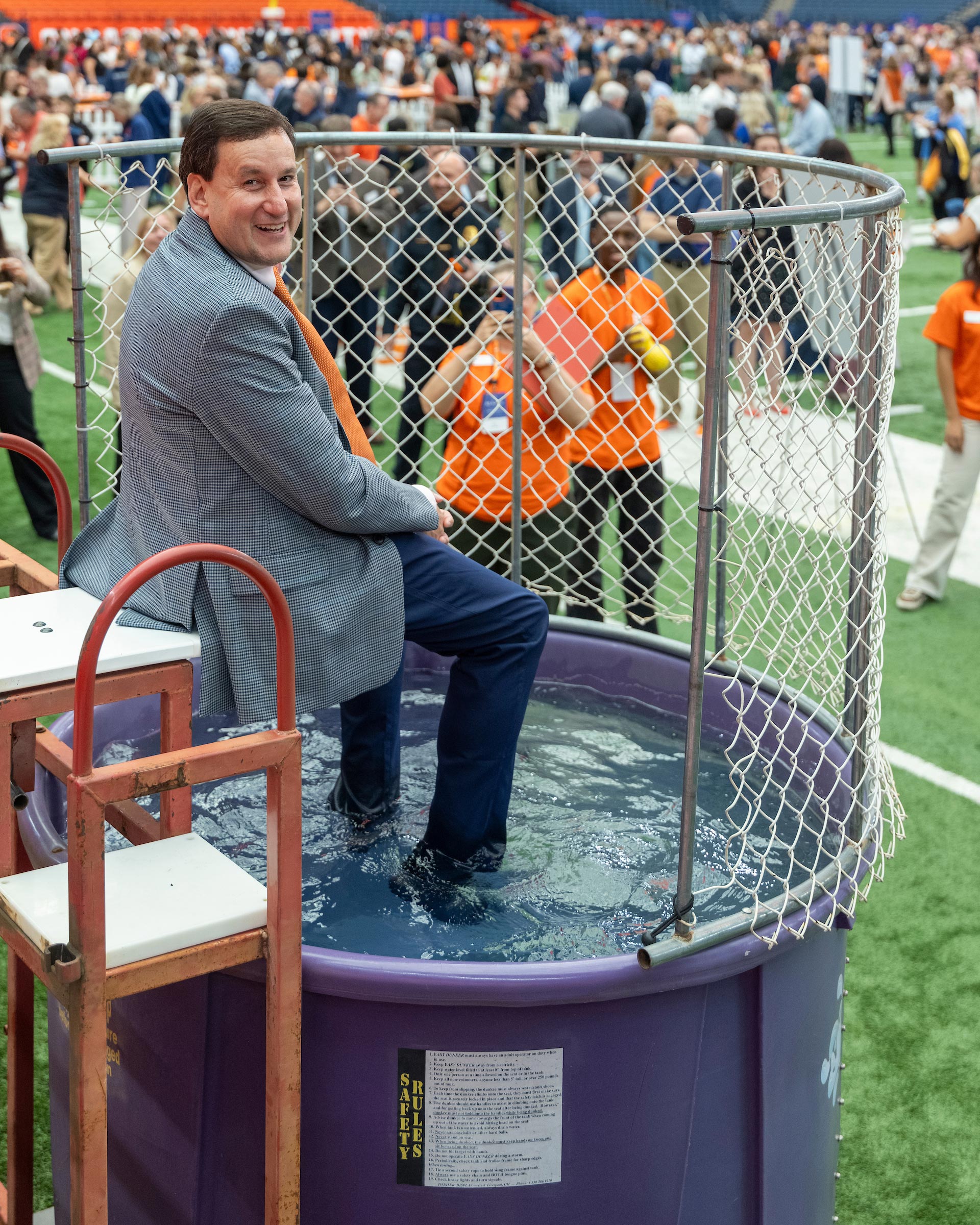 iSchool interim dean Jeff Rubin smiles at the camera as he sits in his suit above the dunk tank waiting for students to throw the balls.