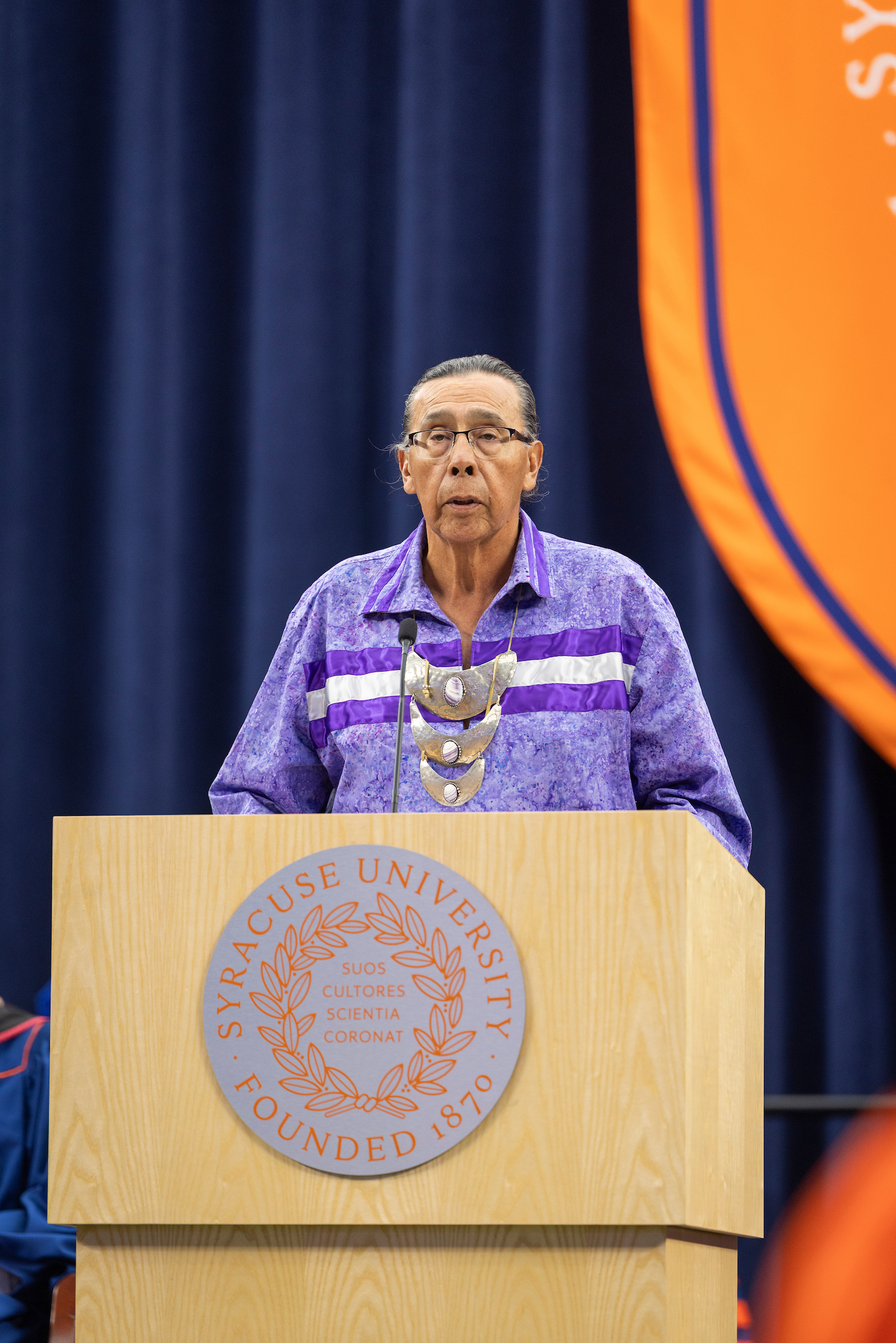 The spiritual leader of the Onondoga Nation stands behind the podium and shares the Thanksgiving prayer at the beginning of the ceremony. 