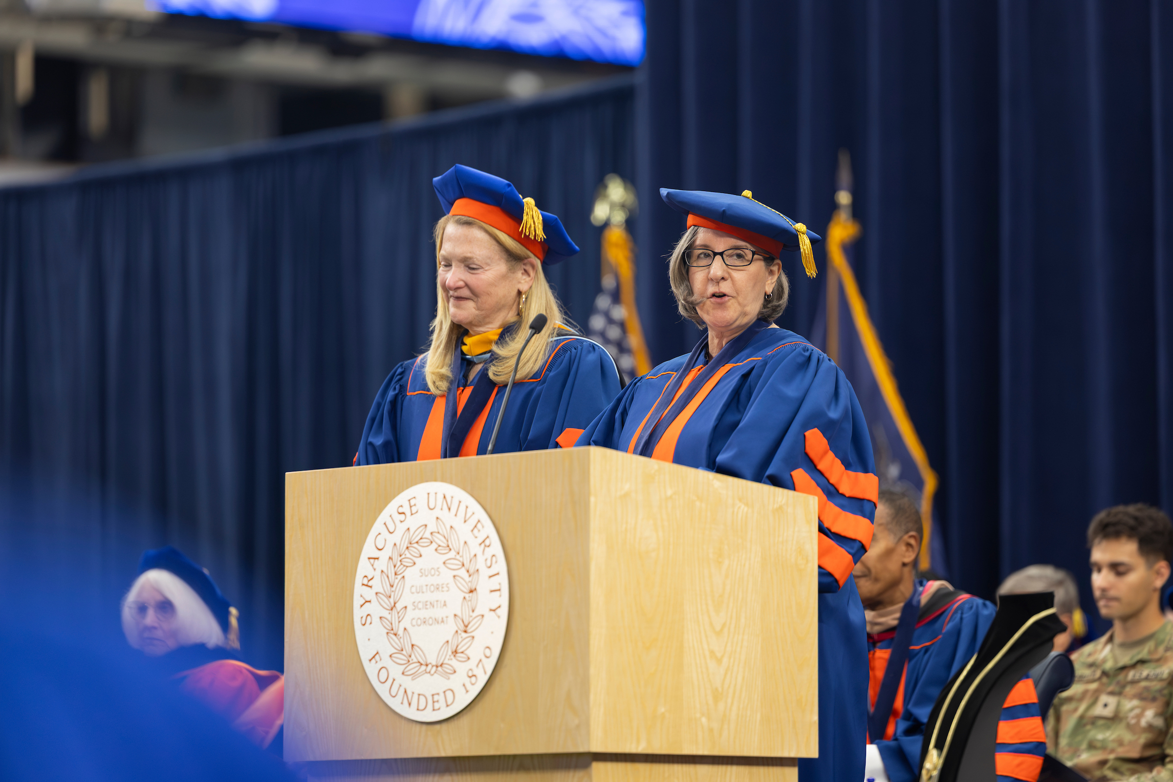 The Syracuse University Board members who served on the search committee speak at the podium during the ceremony.