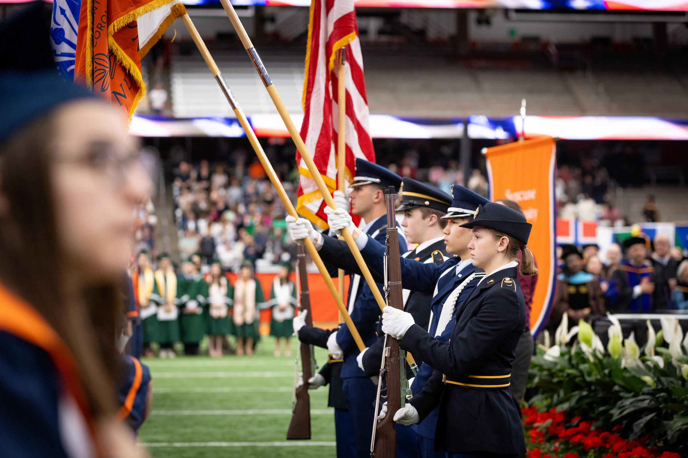 Military dressed individuals holding flags at Commencement
