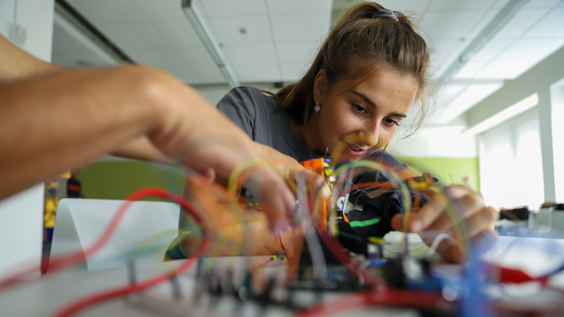A girl looking at wires and adjusting them with her hands