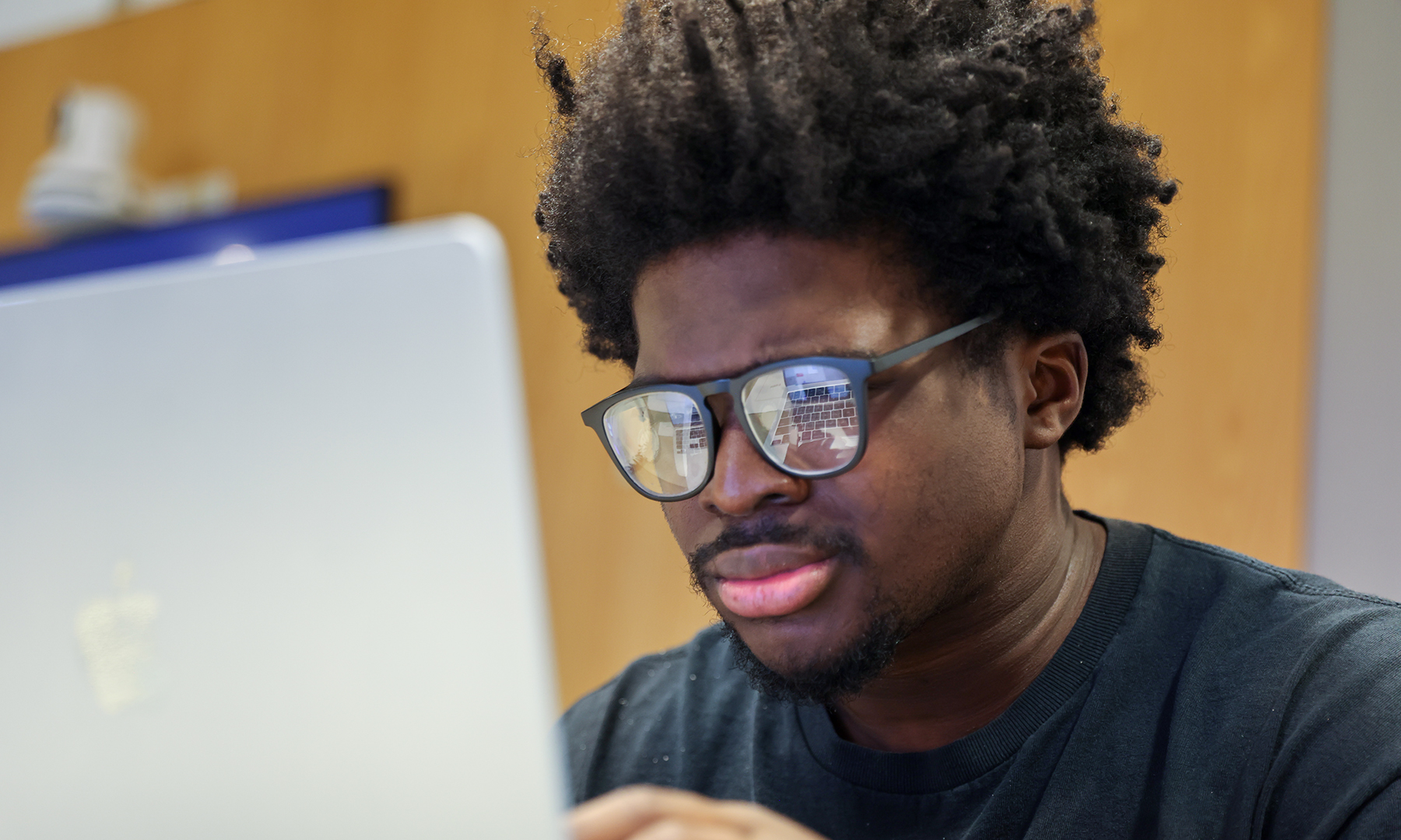 A man wearing glasses looks at a laptop