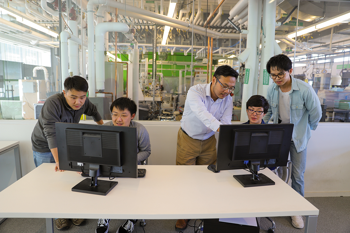 Professor Bing Dong and four students look at computer monitors