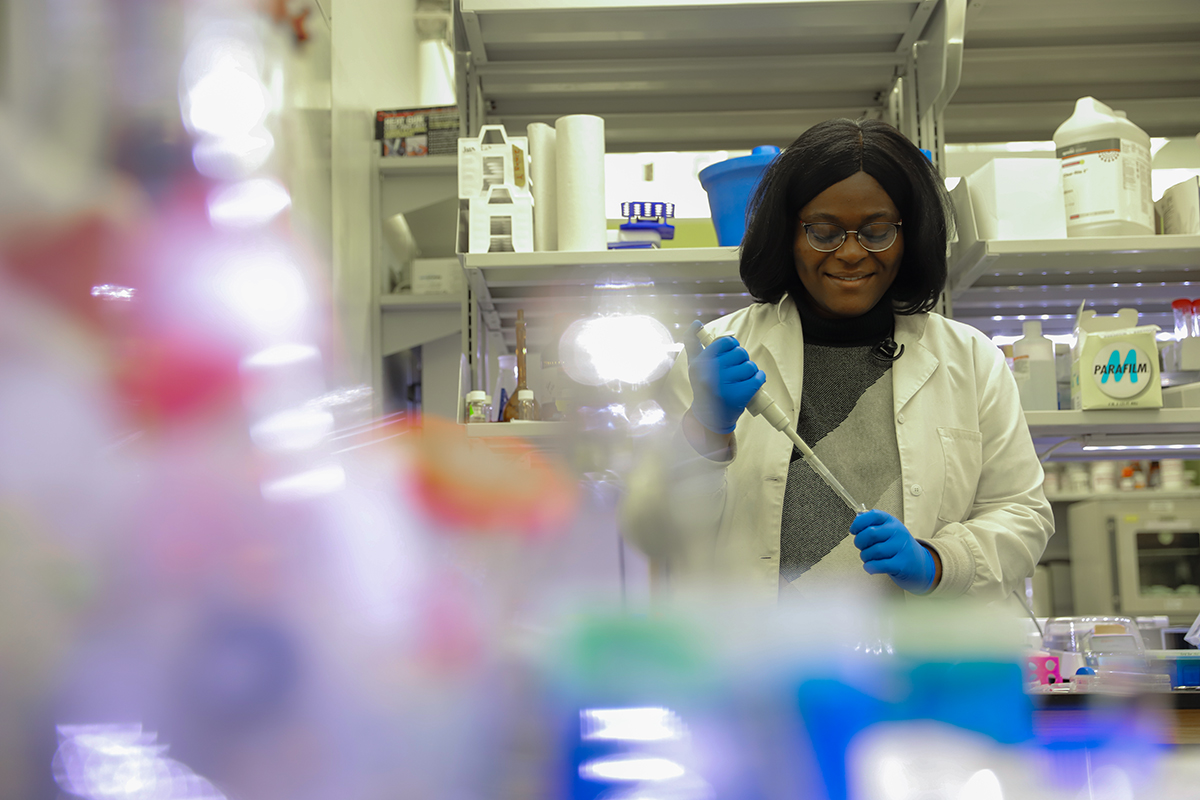 A woman standing in a laboratory injecting an object in her hand