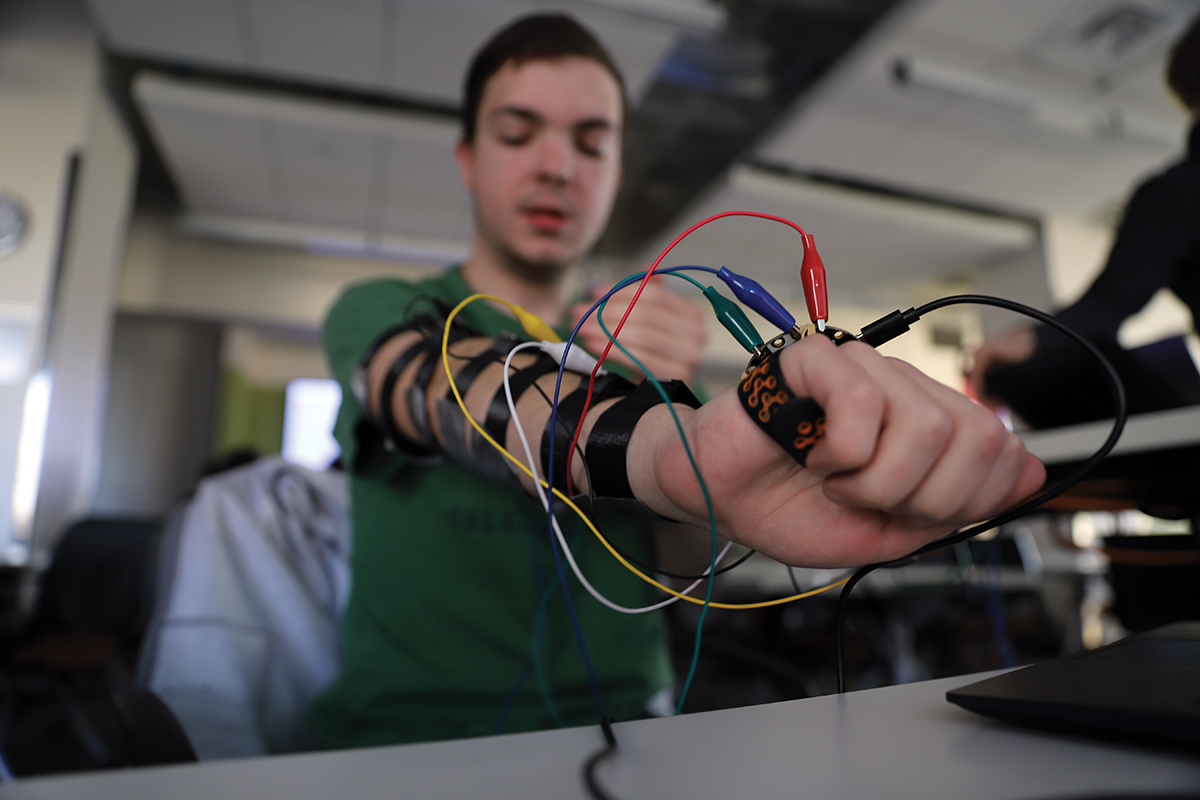 A student adjusting cables and wires attached to a device on their arm