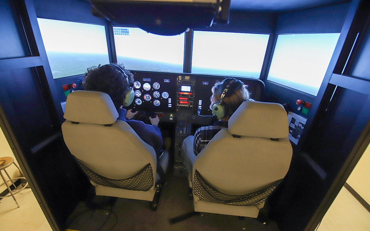 Two people sitting in a flight a fidelity 622i flight simulator