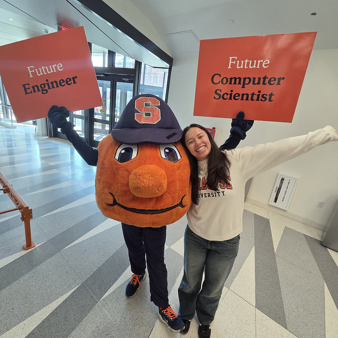 Otto the Orange and a student holding signs that say "future engineer" and "future computer scientist"