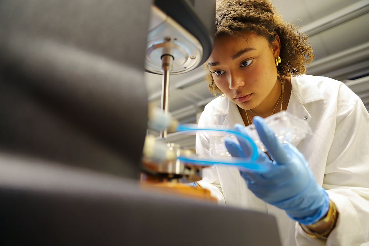 A student examining a piece of equipment in a lab