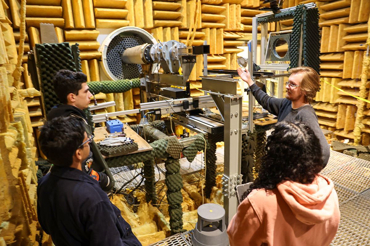 Five students stand in a sub-sonic wind tunnel