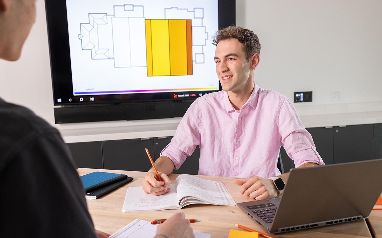 A man sitting at a desk holding a pencil