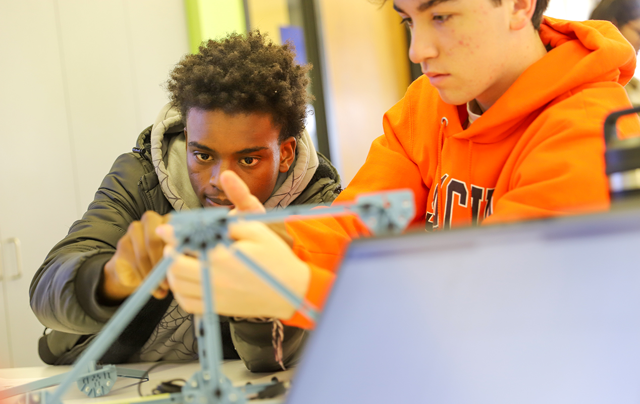 Two boys working on a bridge model 