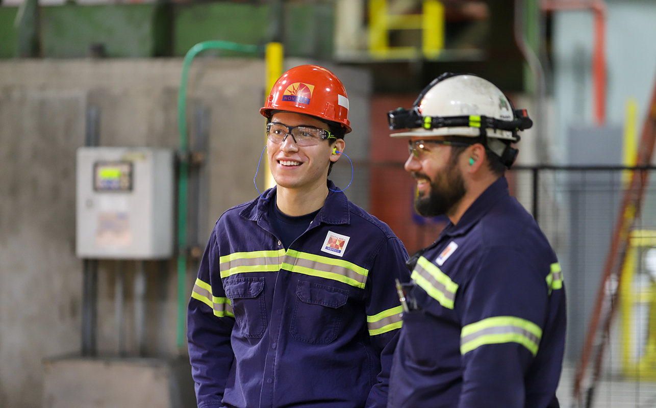 Two men stand and wearing hard hats