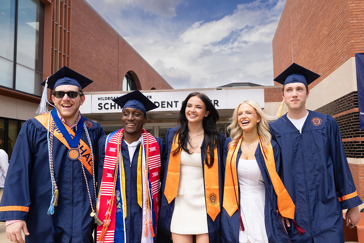 Three men and two women wearing a graduation cap and gown