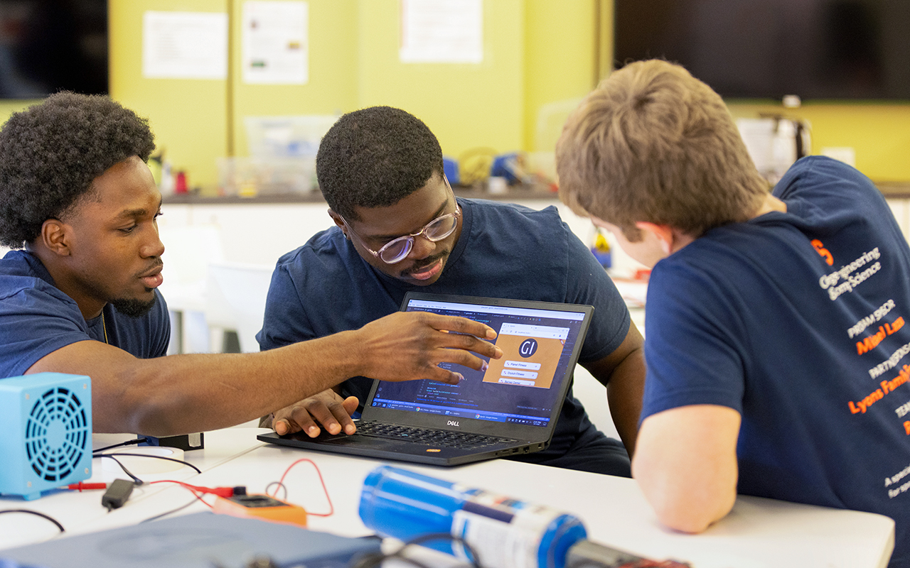 Three men looking at a laptop