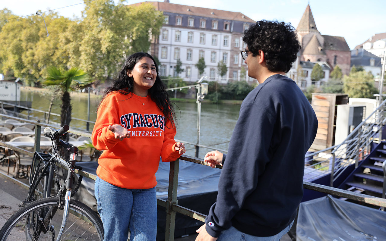 A girl and boy standing on a bridge talking