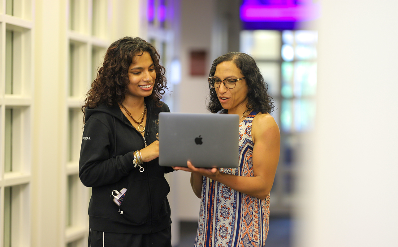 Two women standing and looking at a laptop screen