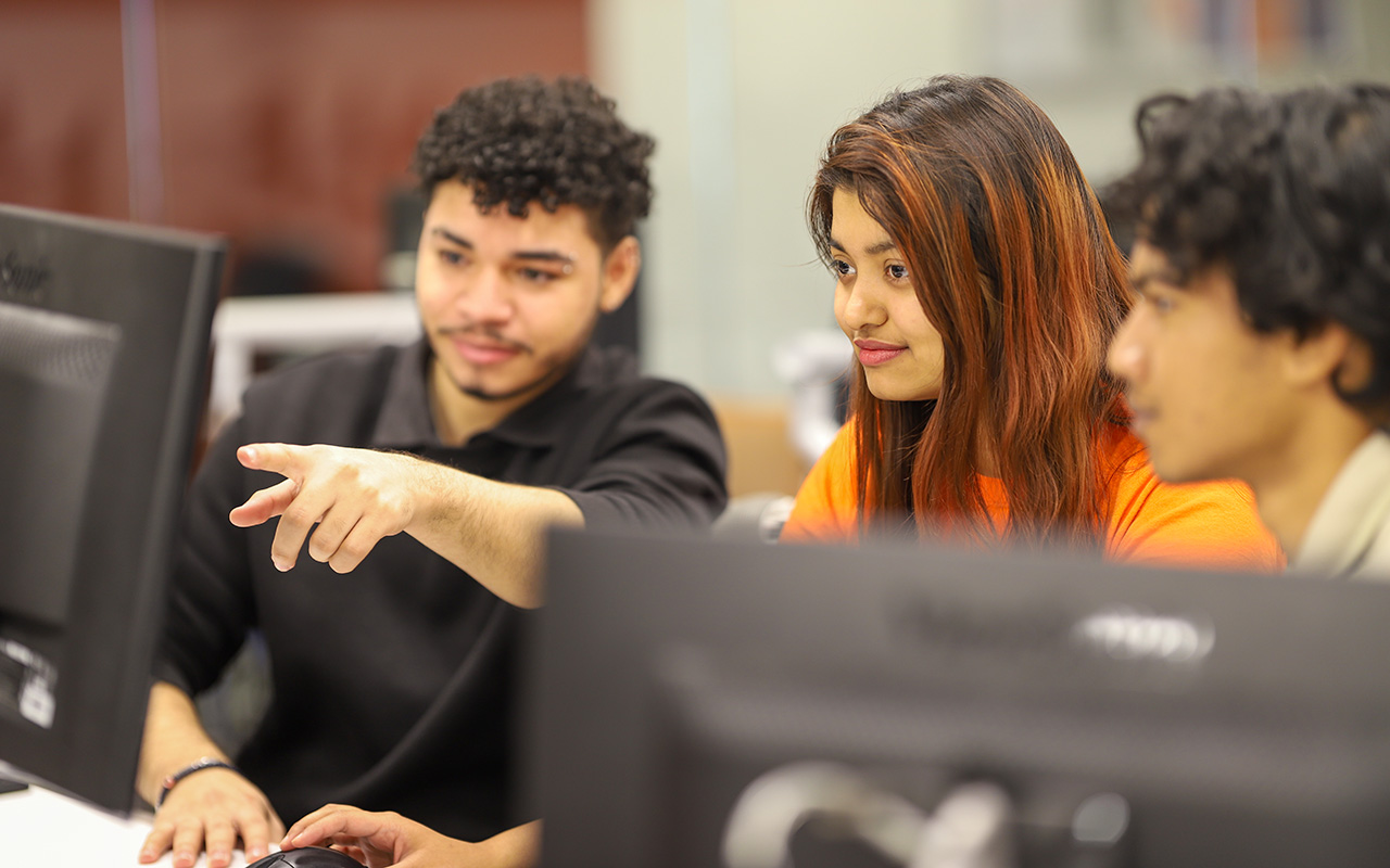 Two boys and a girl looking at a computer monitor