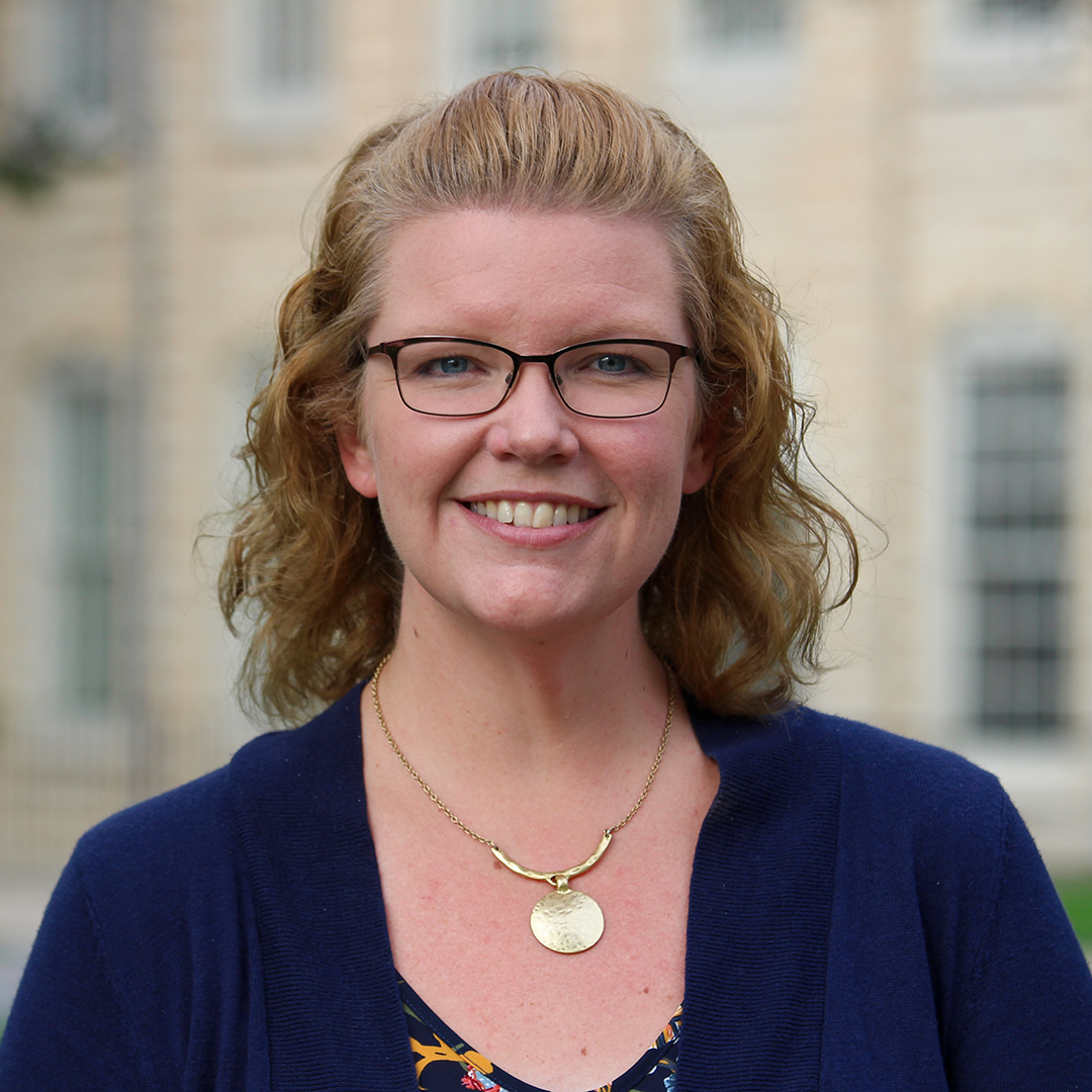 A woman wearing glasses and smiling.