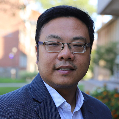 A man with dark, short hair wearing glasses.