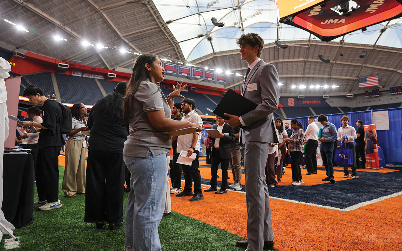 A man and a woman standing facing each other in a crowded arena.