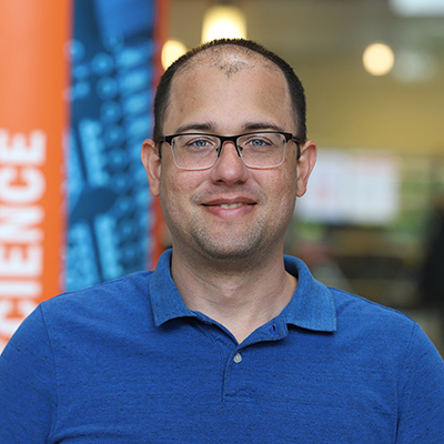 A man wearing glasses and blue polo shirt.