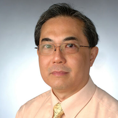 A man with dark hair, glasses and wearing a peach cream color dress shirt.