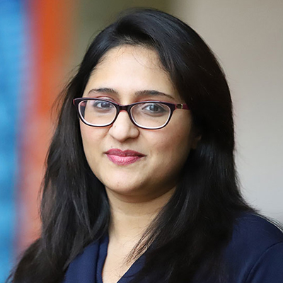 A woman with dark hair wearing glasses.