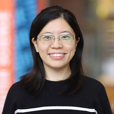 A woman with dark hair wearing glasses and black sweater.