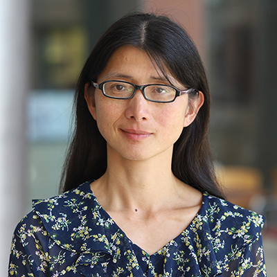 A woman with long dark hair, wearing glasses and floral print dress.