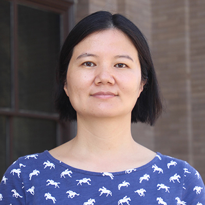 A woman with medium length dark hair wearing a blue shirt with a white horse pattern. 