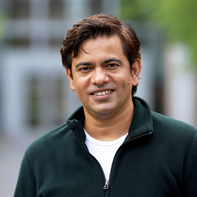 A man smiling and wearing a green quarter zip over a white shirt.