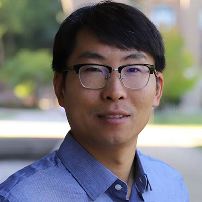 A man with dark hair, and wearing glasses and blue dress shirt.