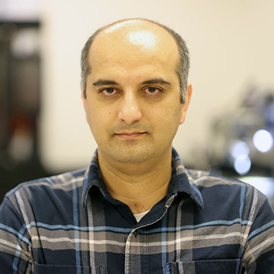 A man without hair wearing a plaid shirt.