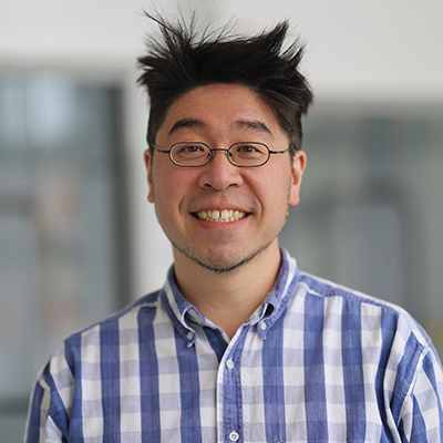 A man wearing glasses with spiked hair. He is smiling.