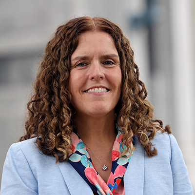 A woman with curly brown hair smiling.