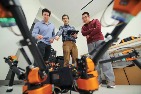 Three men standing and pointing at a drone