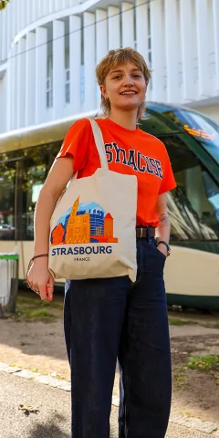 A woman standing in front of a commuter train holding tote