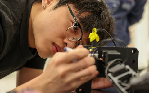 A man's face looking closely at electronic equipment.