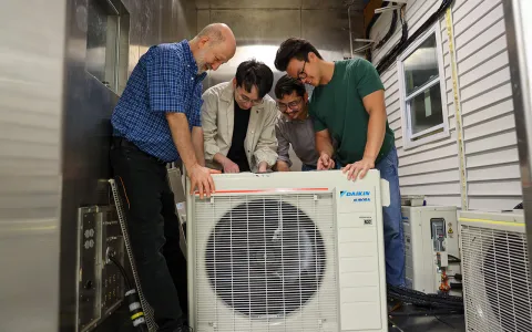 Four men looking at  an air conditioner.