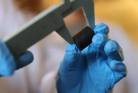 A researcher using a tool to measure a lunar building material sample