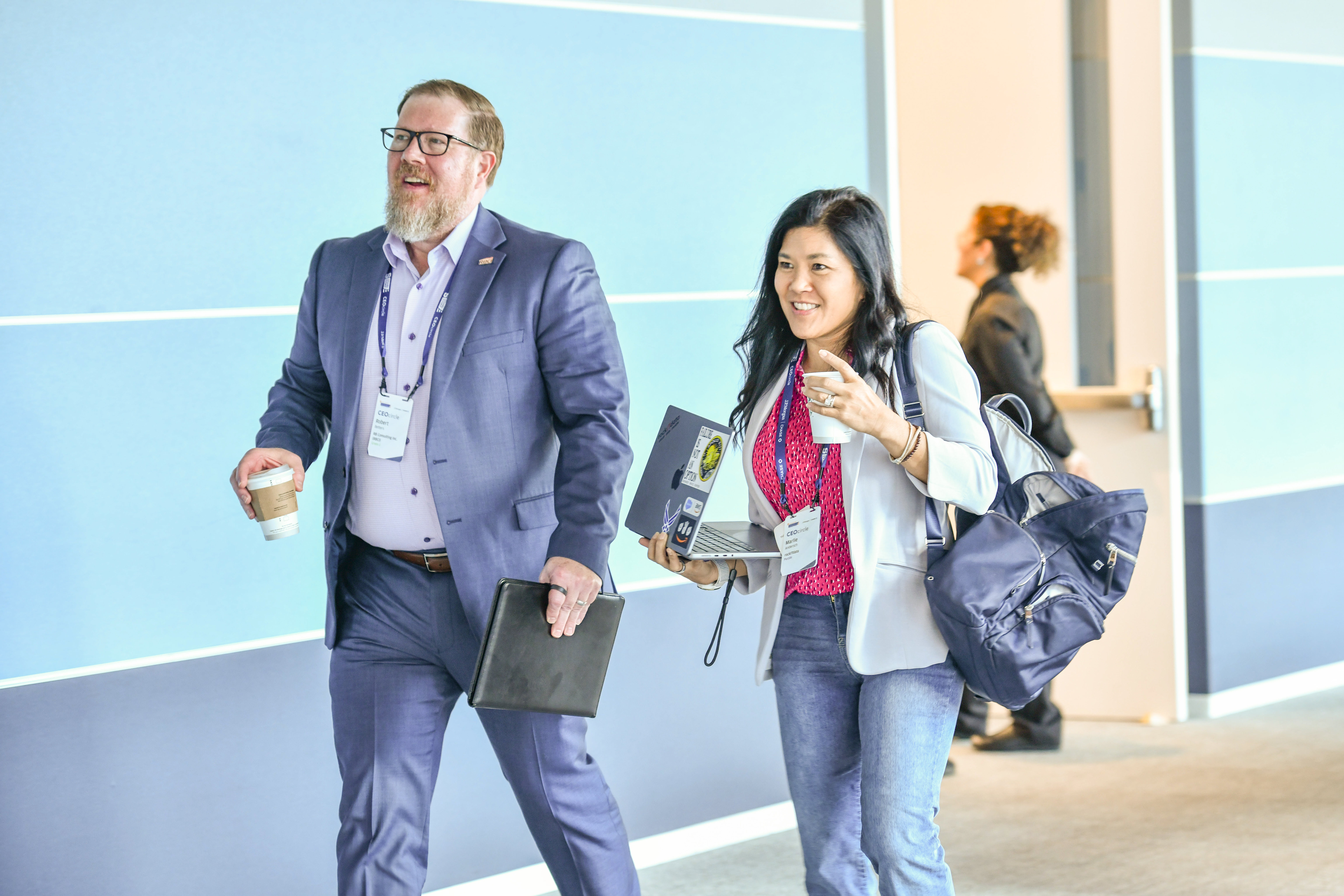 Man and woman in suits talking in a hallway at an IVMF event. 